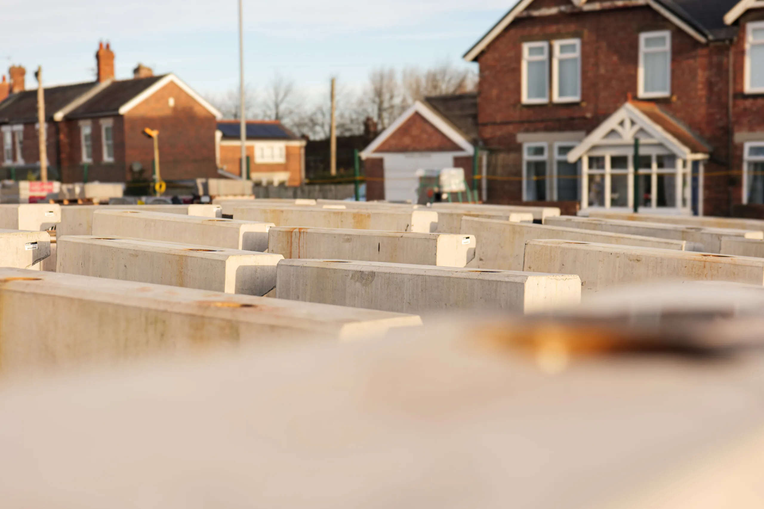 Concrete blocks arranged in rows at a construction site with residential buildings in the background.