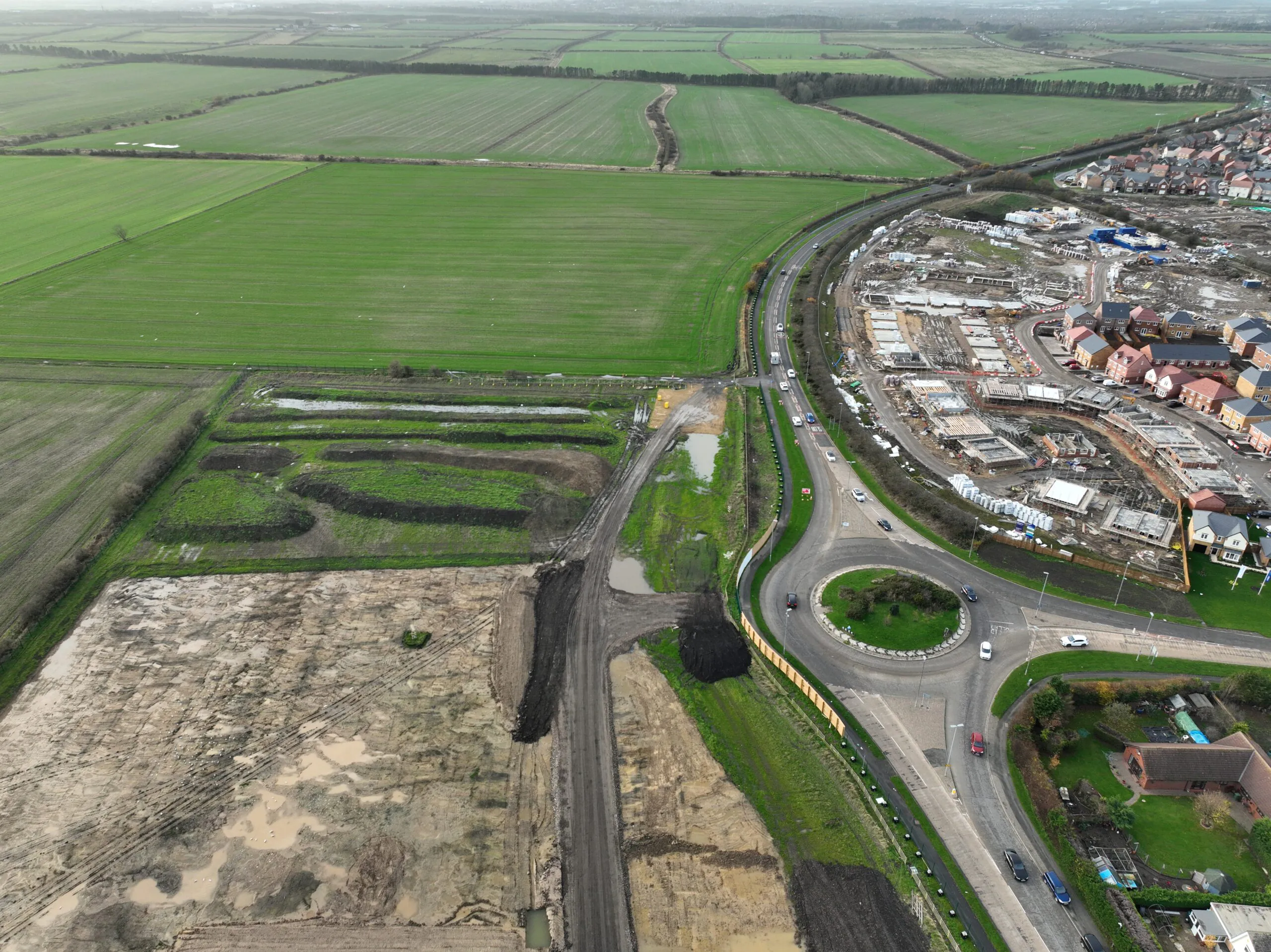 Aerial view of bridge construction with steel components and scaffolding near a road and residential area.