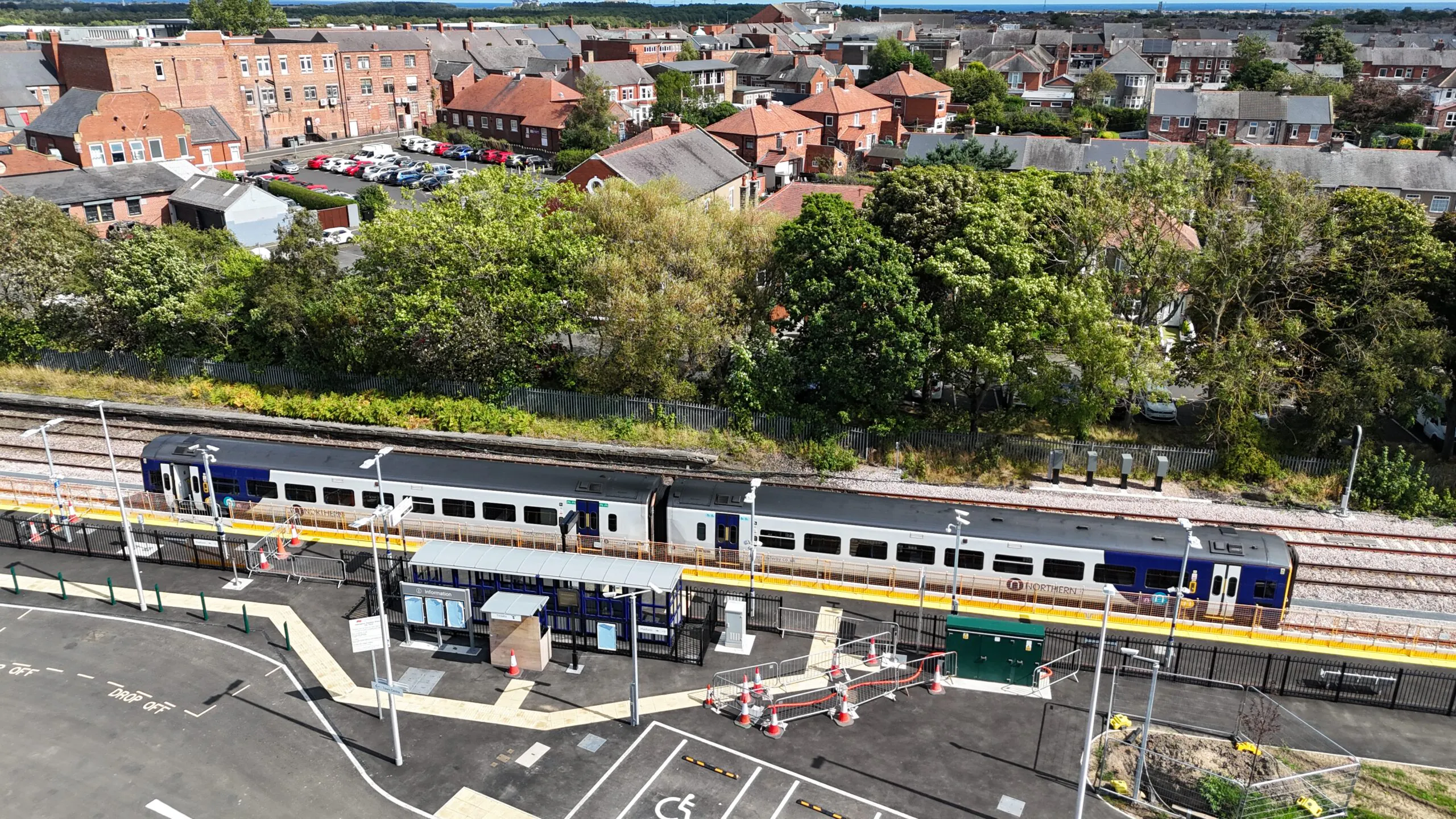 Aerial view of railway infrastructure development near residential buildings with visible construction equipment.