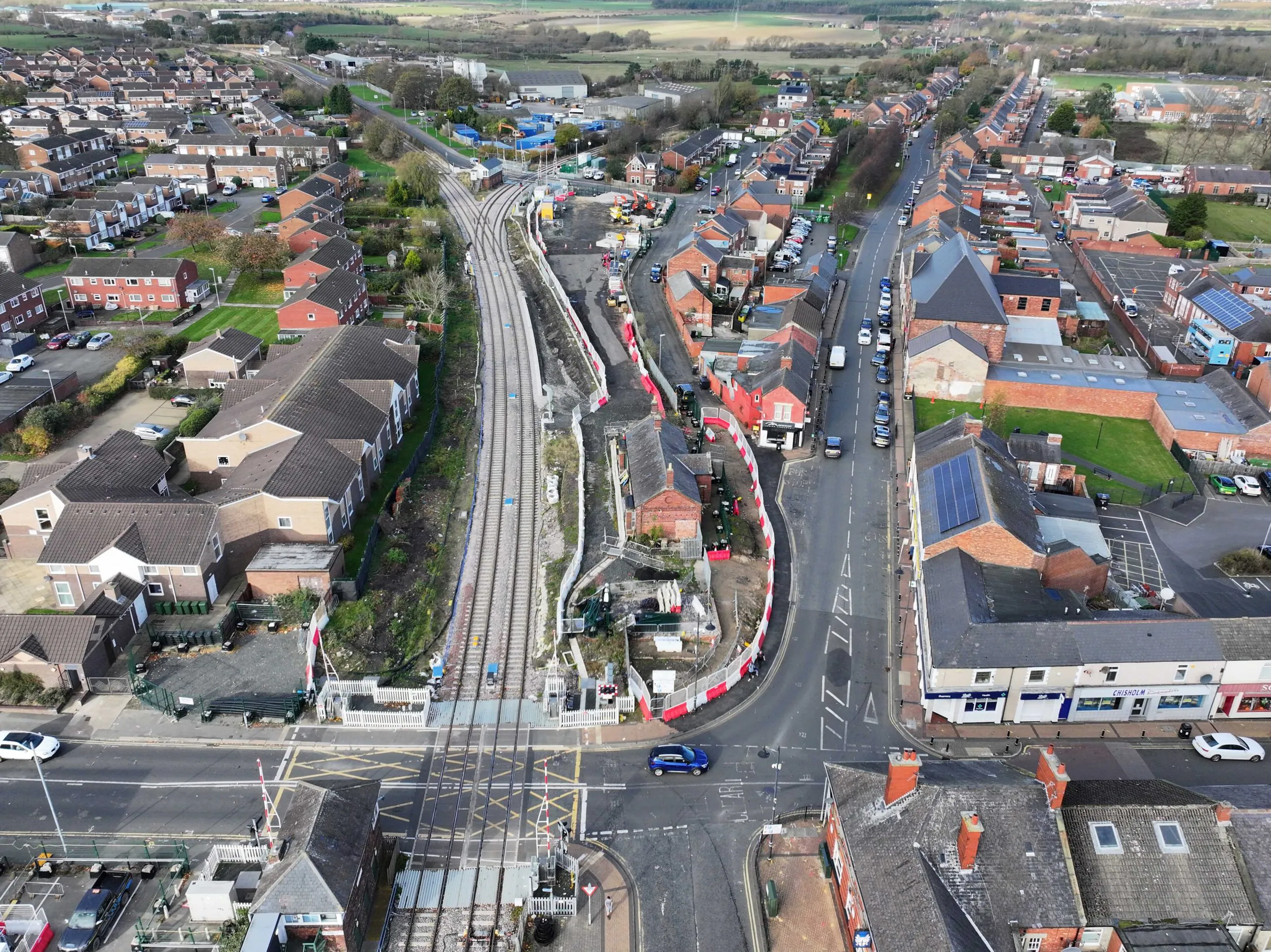 Aerial view of infrastructure development around rail lines intersecting urban neighborhoods with homes and businesses.