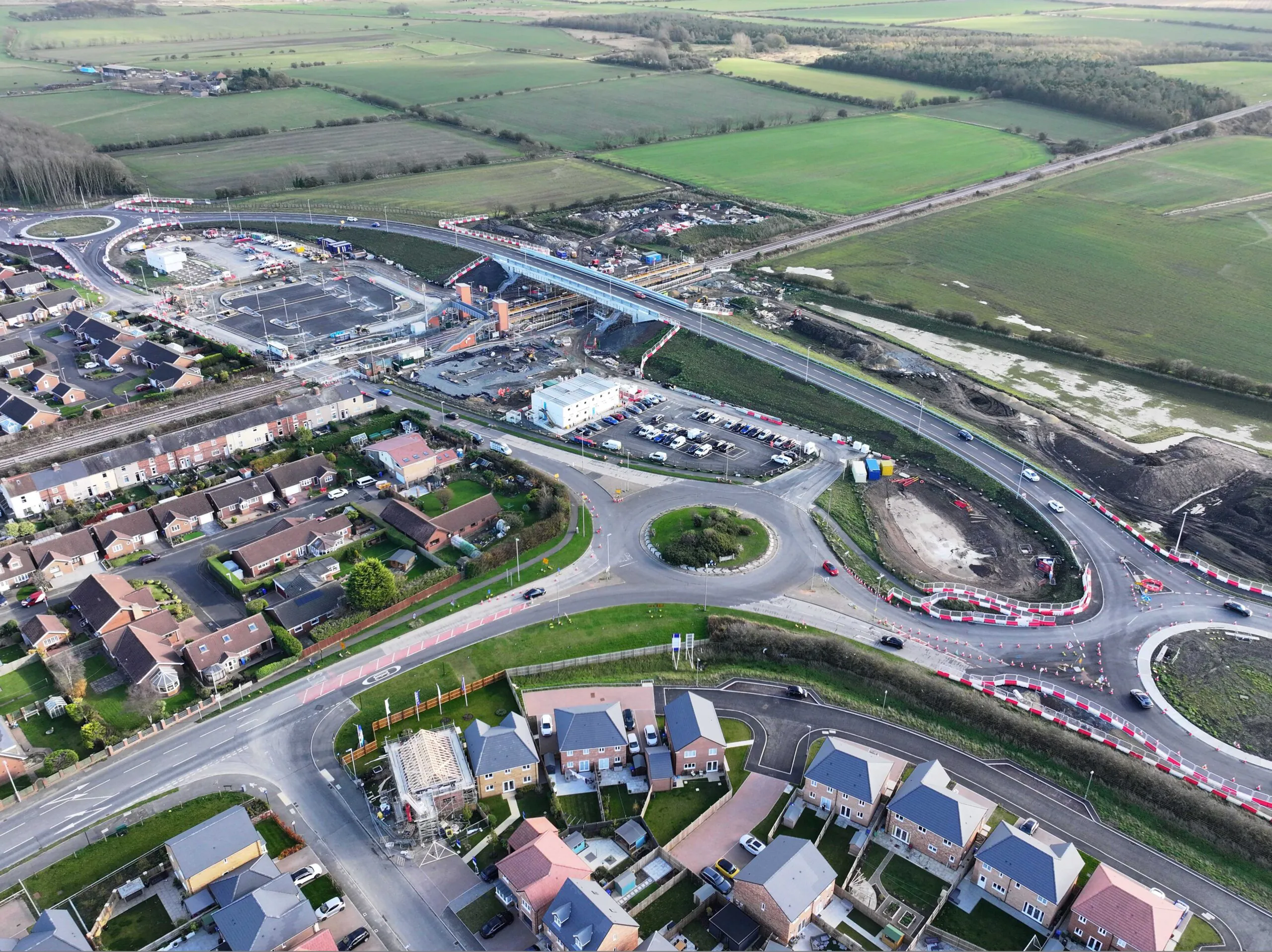 Aerial view of roadwork projects including roundabouts, parking lots, and adjacent residential areas.