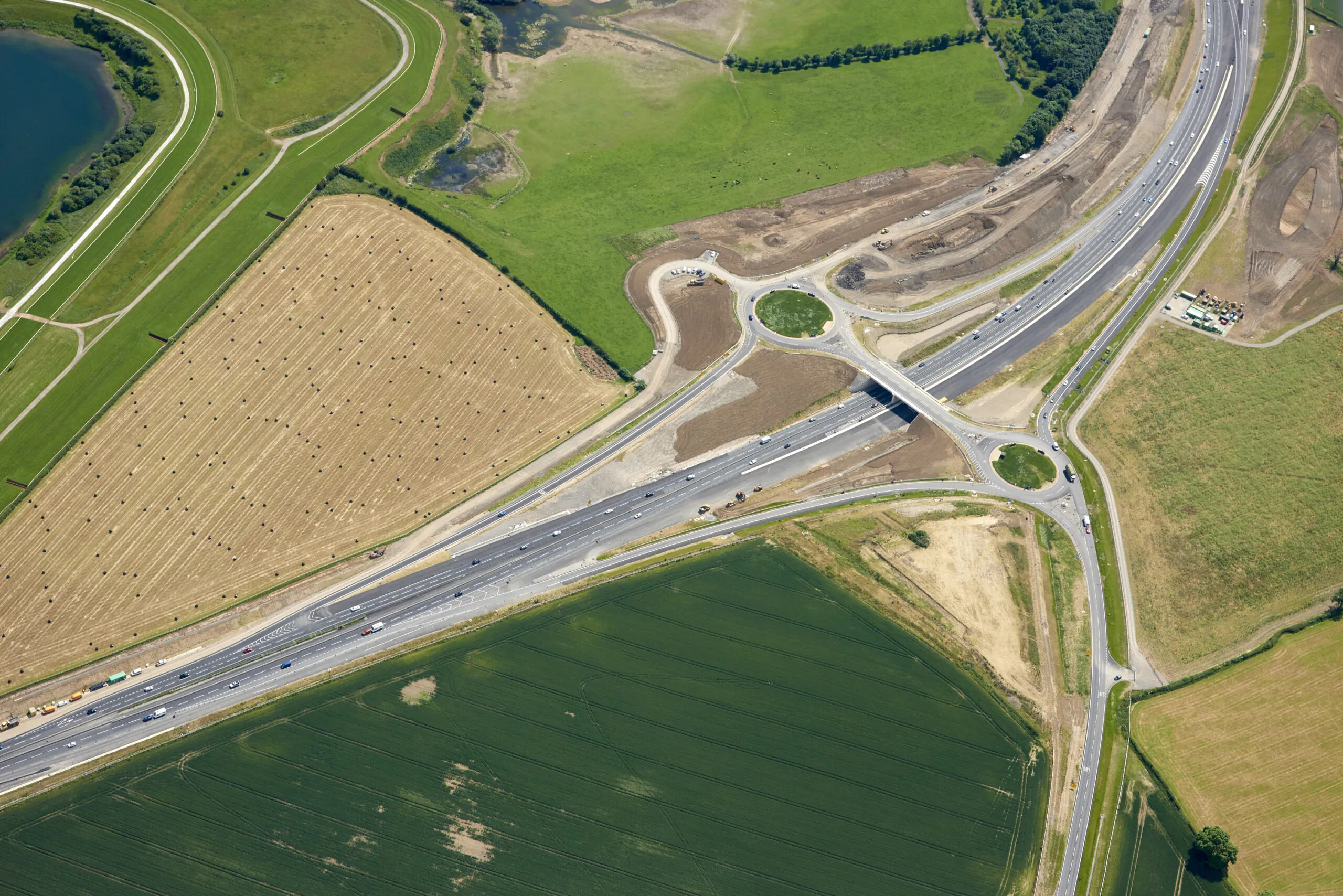 Aerial view of a highway interchange surrounded by agricultural land and green fields.