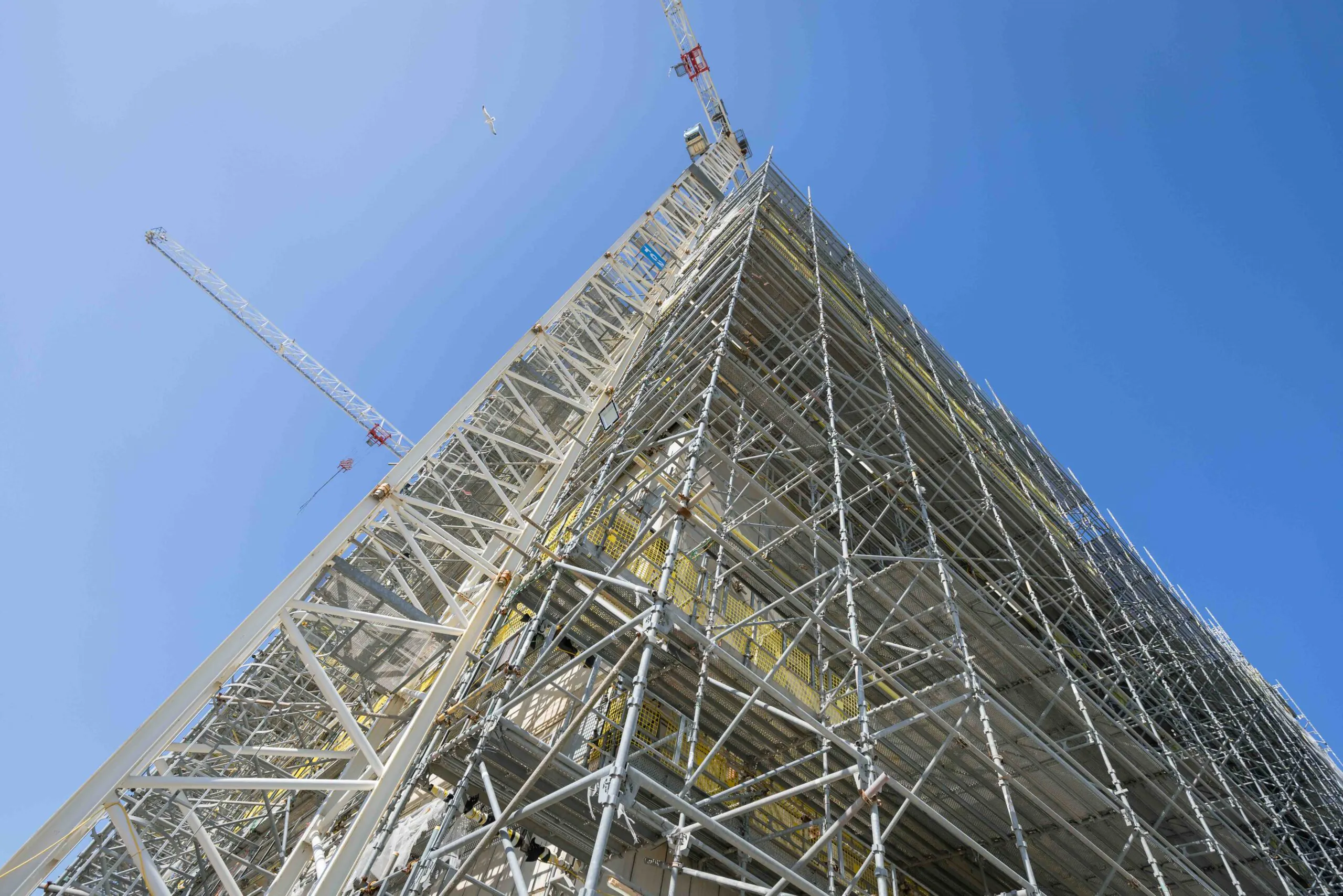 Close-up of scaffolding surrounding a tall structure under construction, highlighting the metal framework.