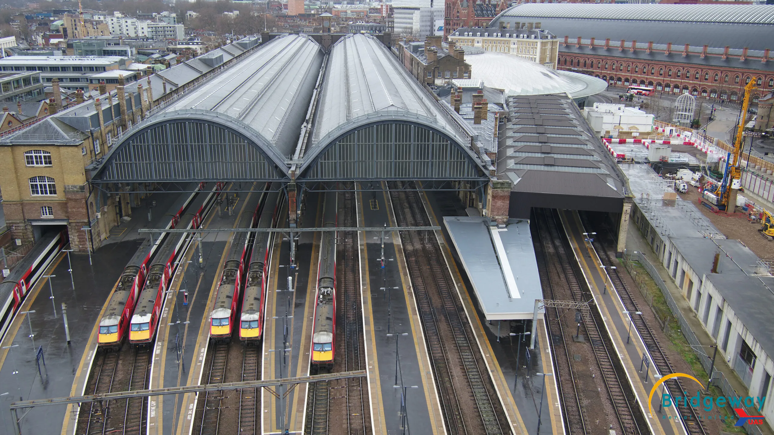 Aerial view of King's Cross railway station showing multiple train tracks leading into large arched roofs from a different angle.