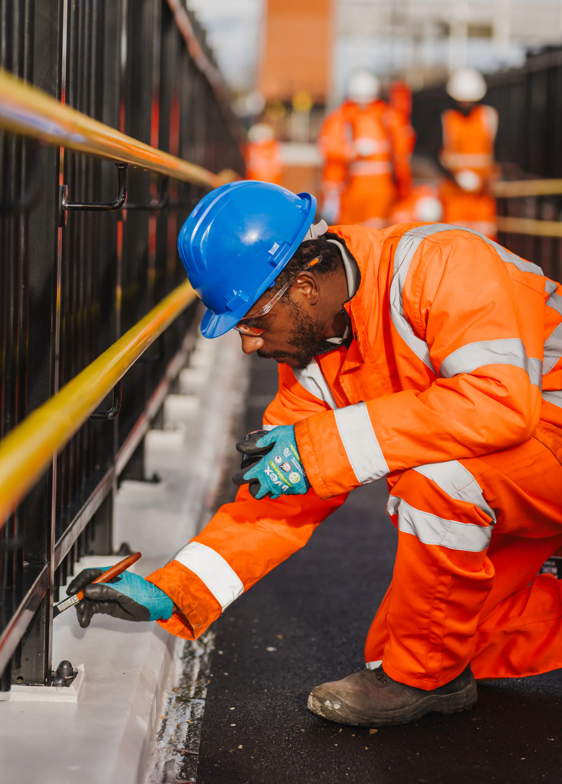 Worker in high-visibility clothing walking along a newly constructed platform with safety fencing.