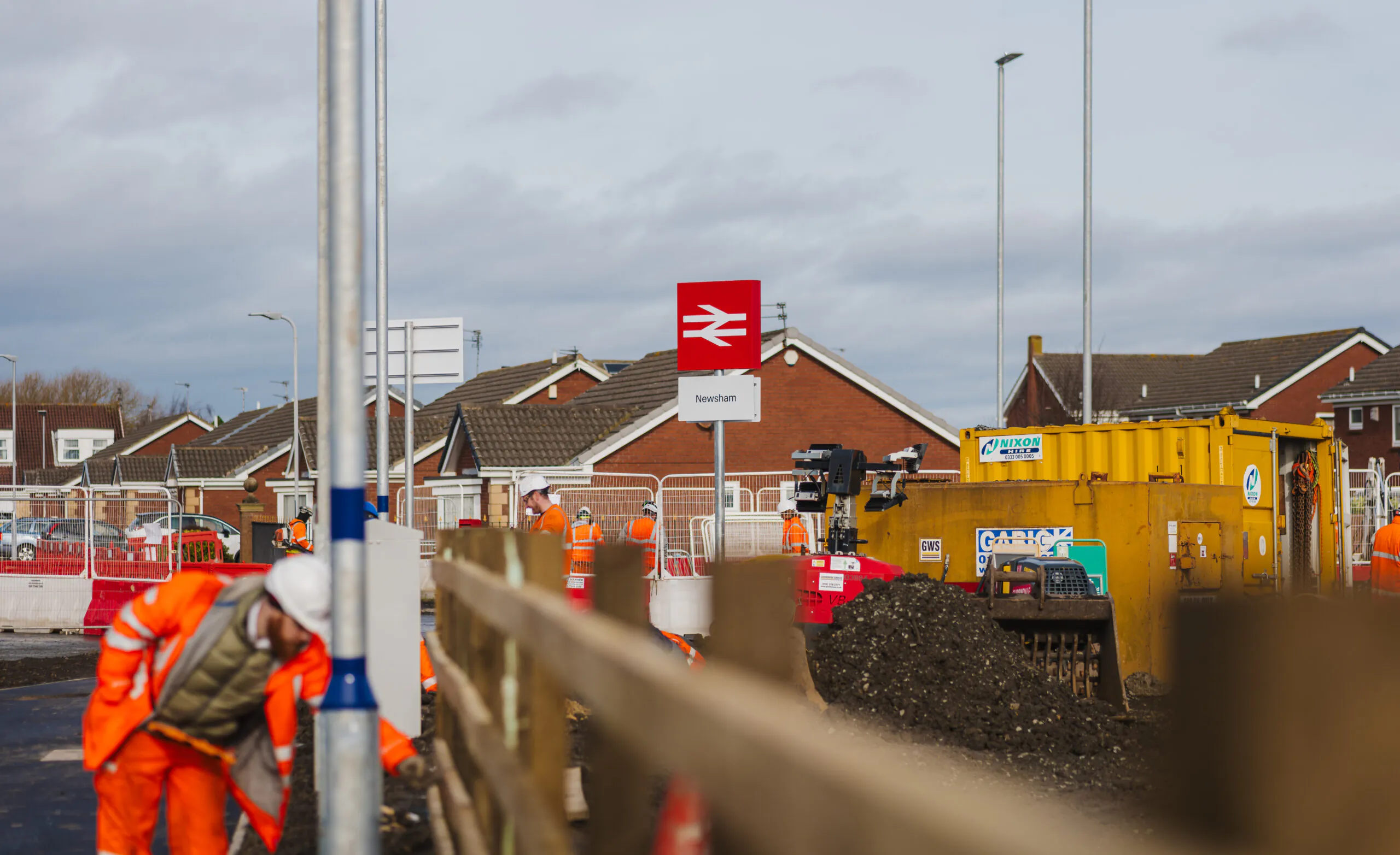 Worker inspecting signage and platform edge markings at a newly built train station platform.