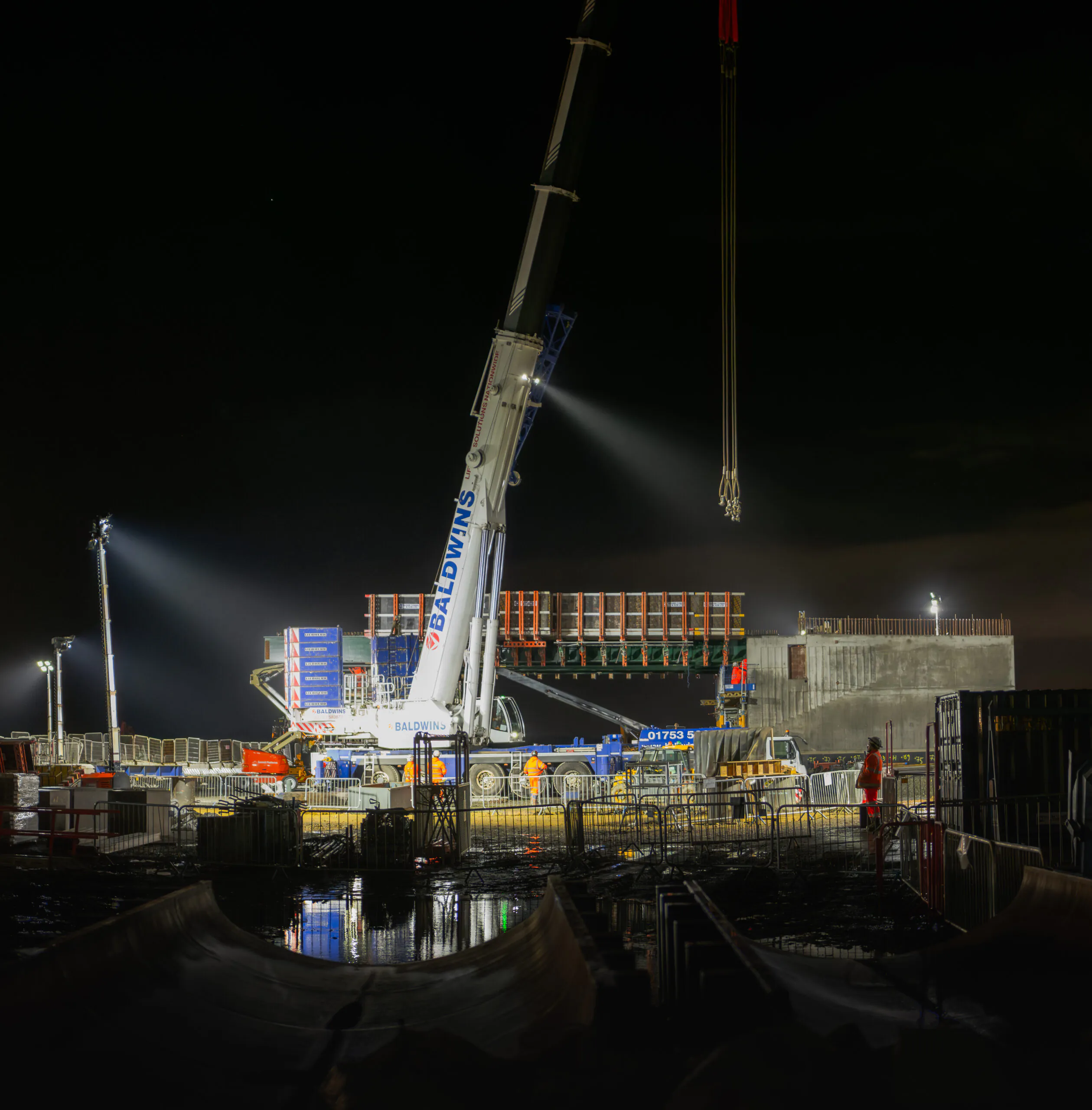 Installed west deck of a bridge with protective barriers and scaffolding at a construction site.