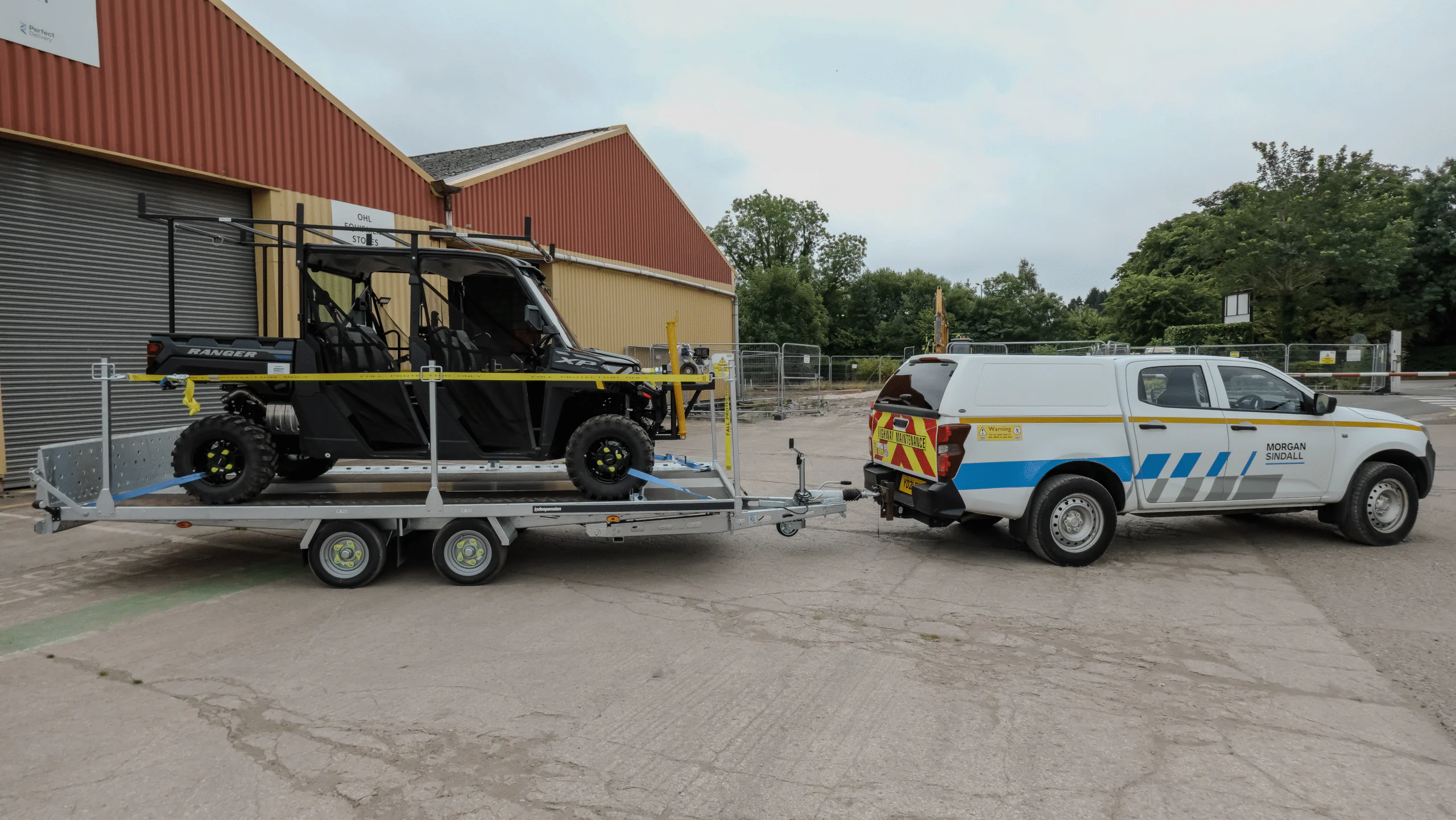Utility vehicle towing an off-road vehicle on a trailer, both marked with Morgan Sindall Infrastructure branding.