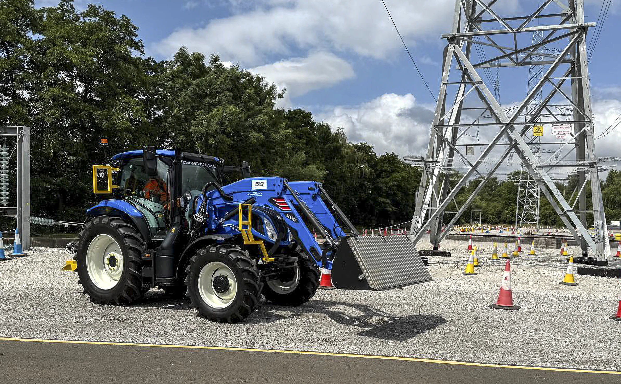 Blue tractor with winching gear branded "Townson Tractors," parked outdoors near trees and construction equipment.