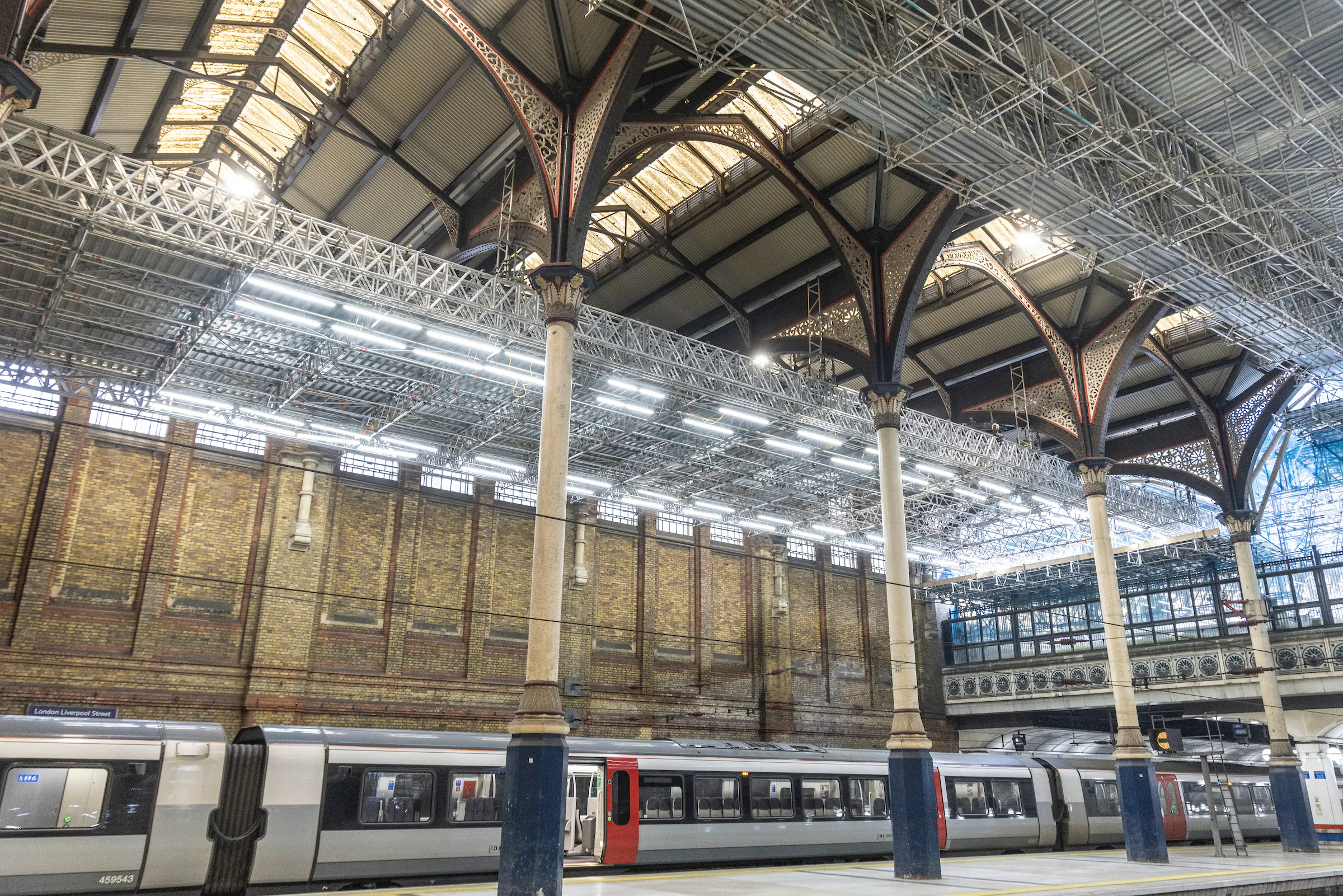 Interior of Liverpool Street Station showing scaffolding and renovation work across platforms.