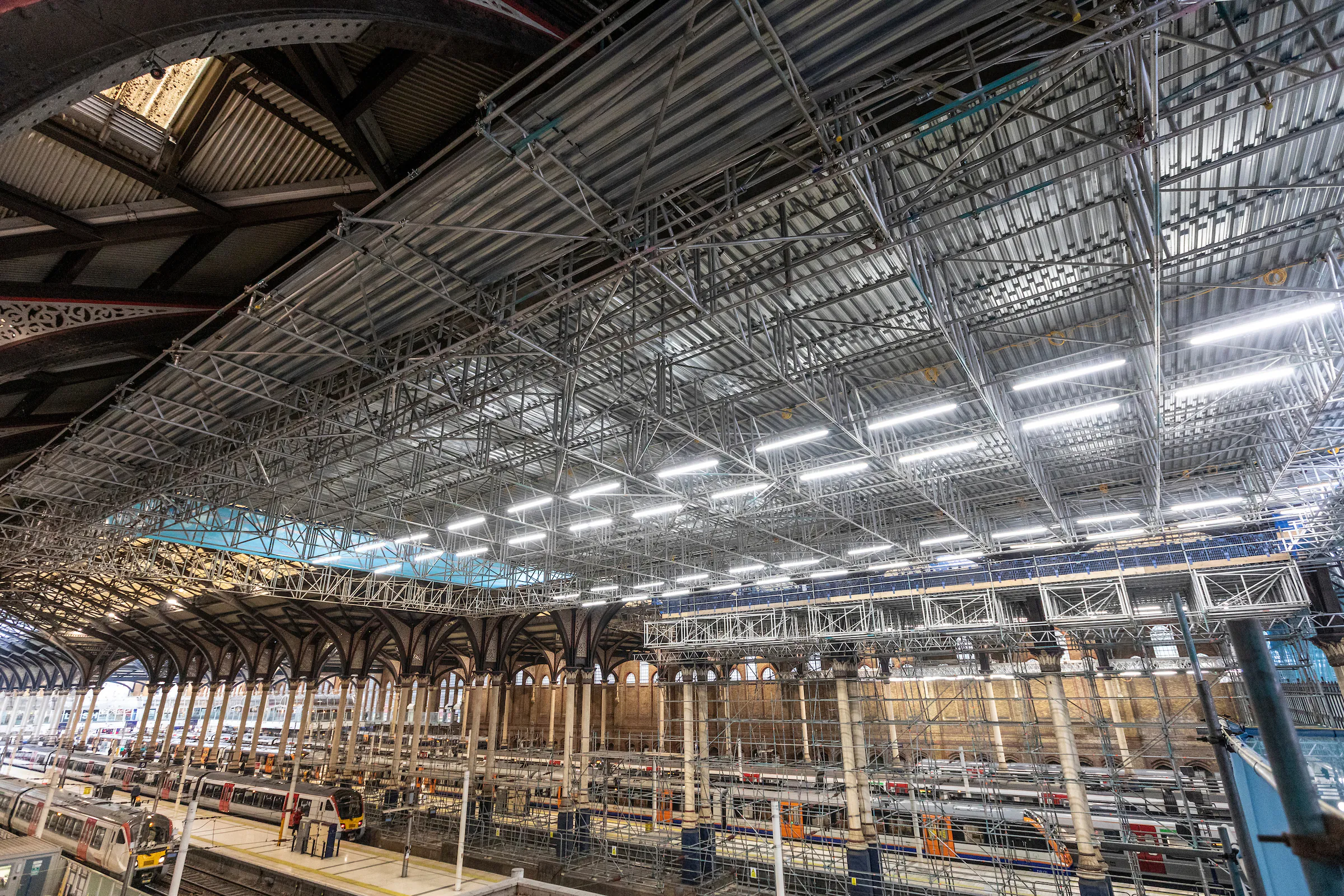 Interior of Liverpool Street Station with scaffolding and renovation work underway.