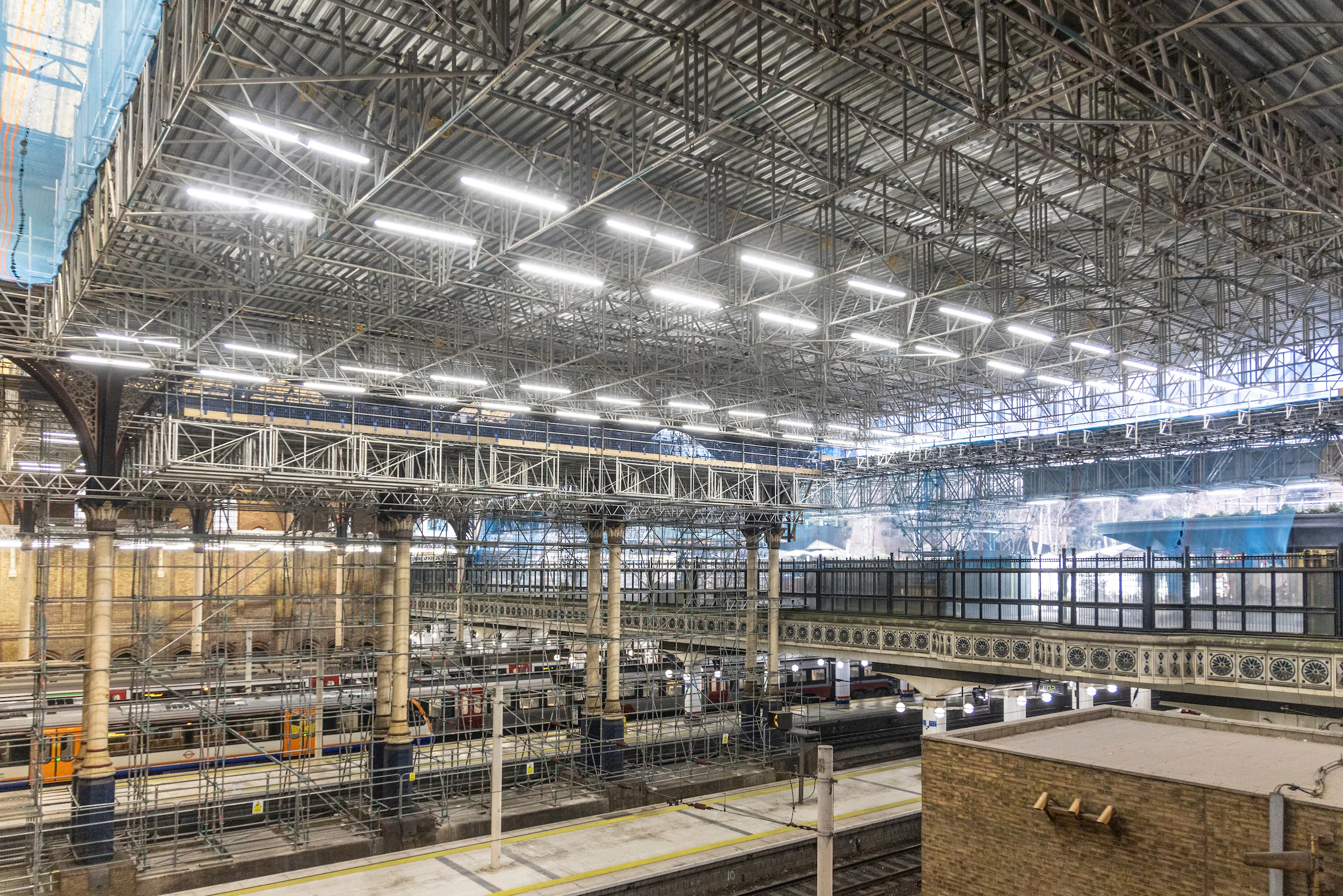 Renovation work inside Liverpool Street Station with scaffolding structures and construction materials.