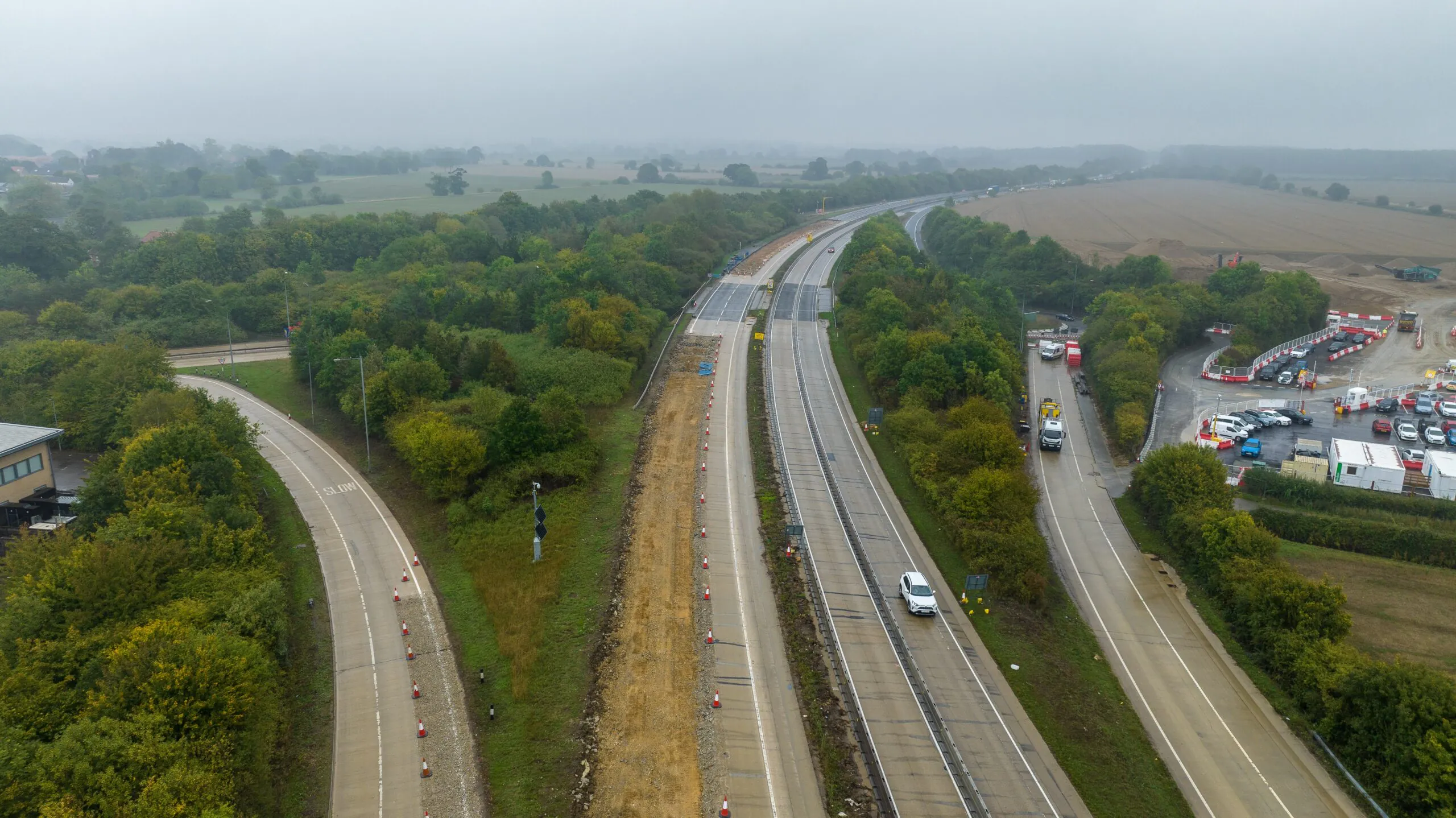Aerial view of a multi-lane highway surrounded by greenery, with traffic flowing smoothly in both directions.