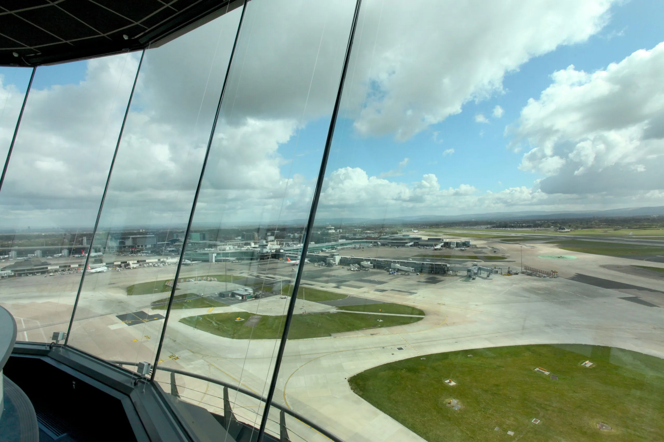 Interior of a modern airport control tower with panoramic views of runways and taxiways below.