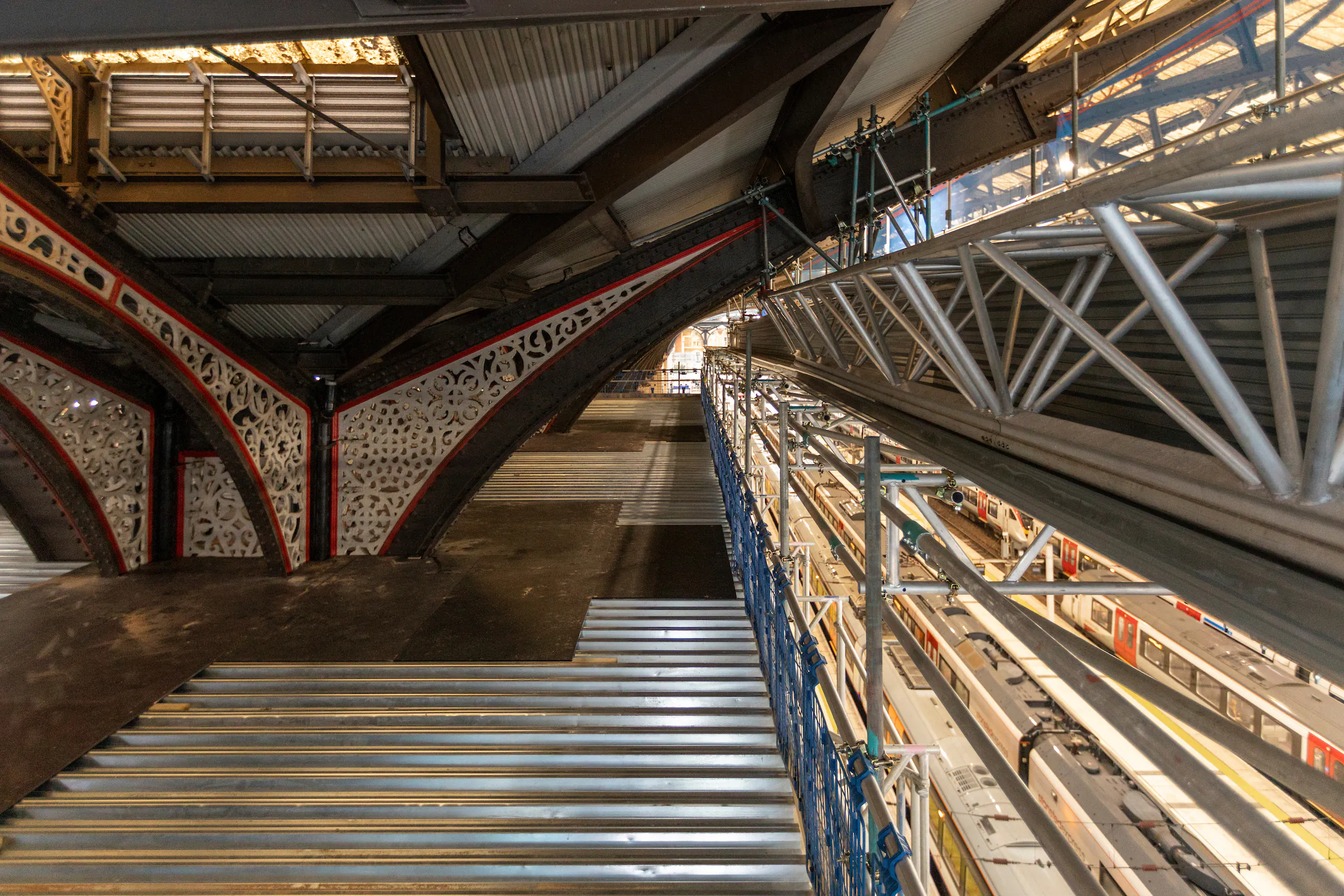 Interior of Liverpool Street Station showing scaffolding structures supporting ceiling and platform renovations.