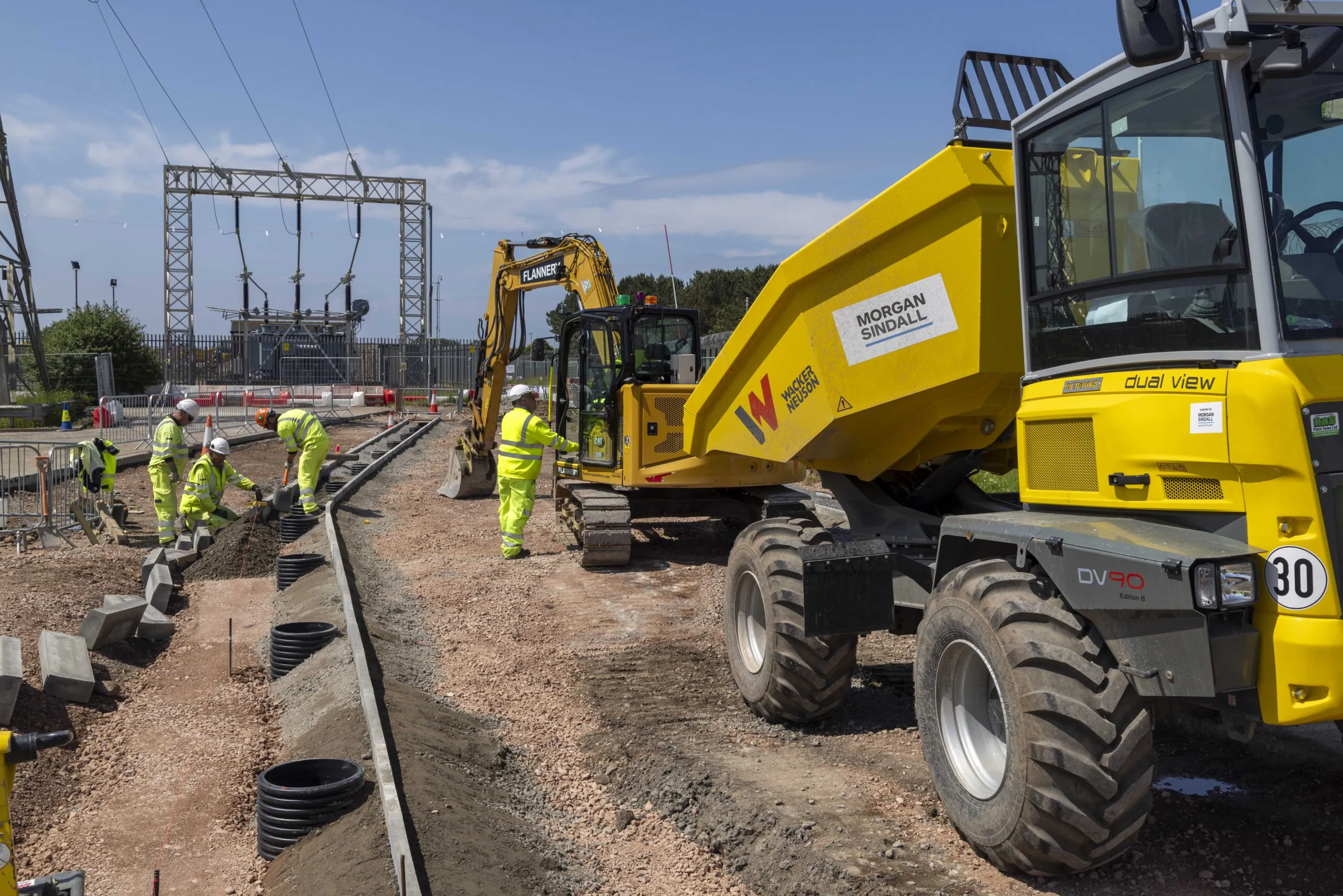 Worker in high-visibility clothing reinforces steel bars for concrete pouring at an outdoor construction site.