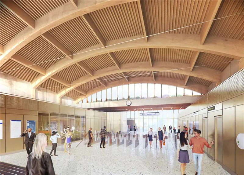 Interior of a spacious building with arched timber ceilings, large windows, and people walking or standing in groups.