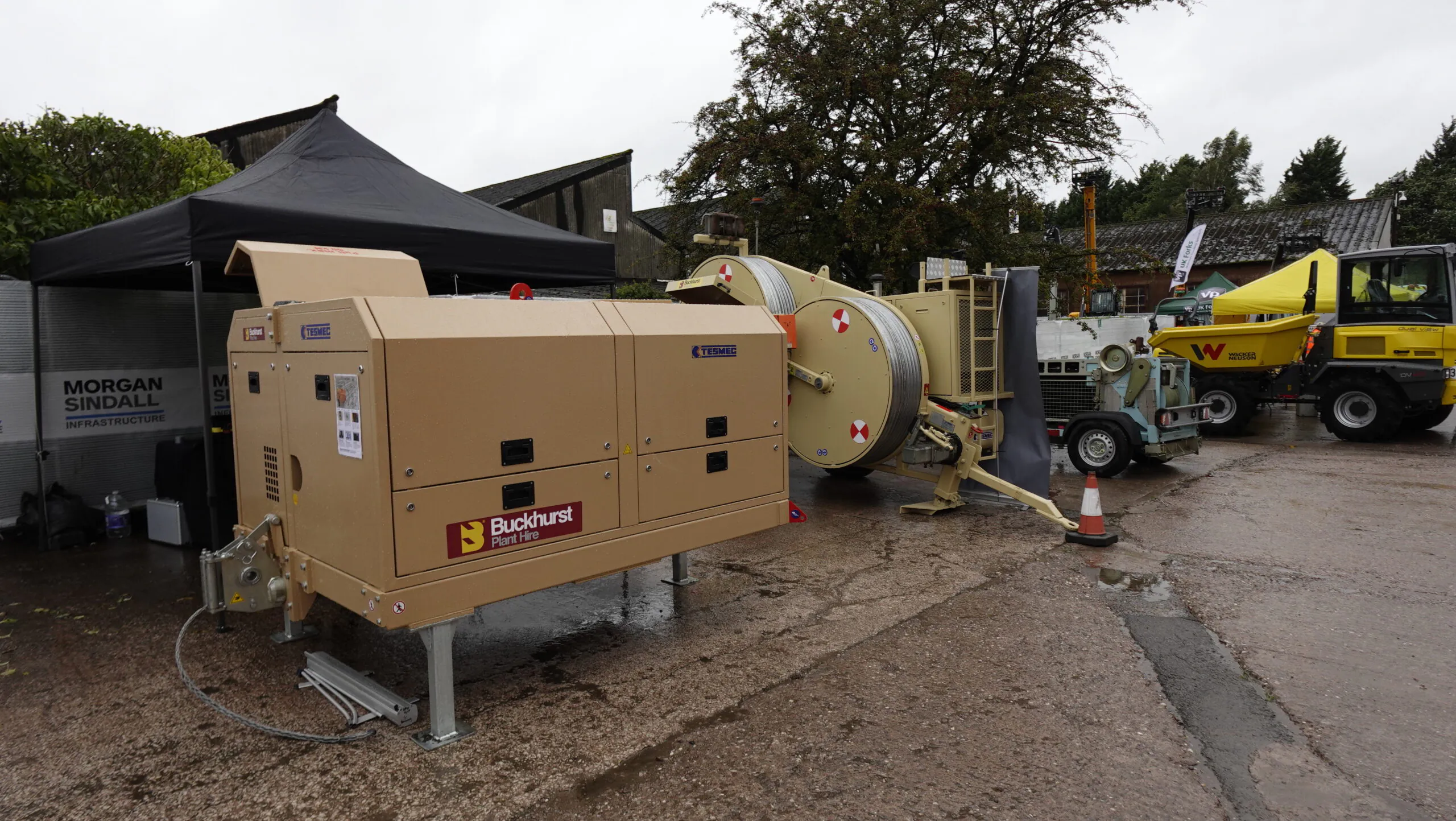 Outdoor machinery setup with equipment from Buckhurst Plant Hire Ltd under tents, including generators and cable reels.
