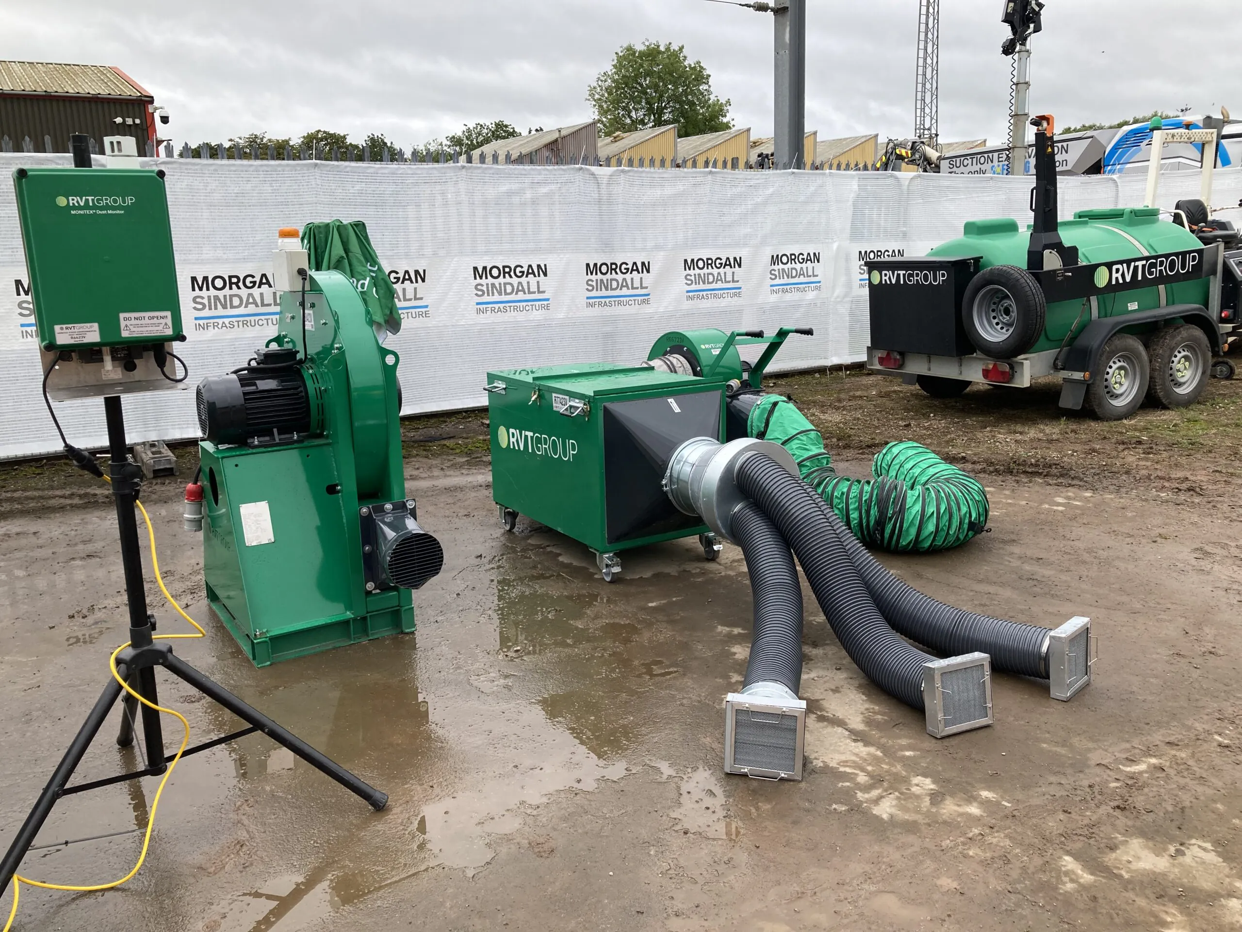 Green industrial equipment from RVT Group set up outdoors on wet ground, including large hoses and machinery components.