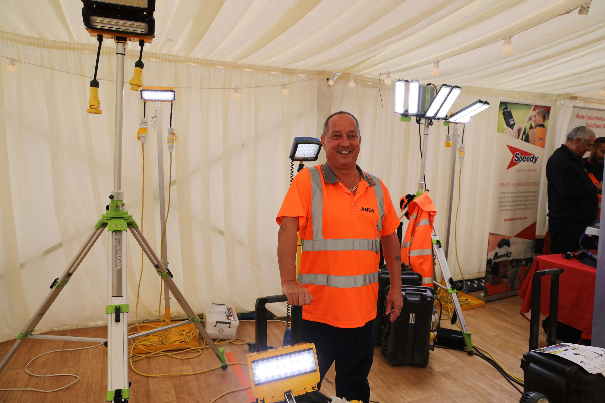 Indoor exhibition booth featuring lighting equipment and a person in an orange high-visibility vest.