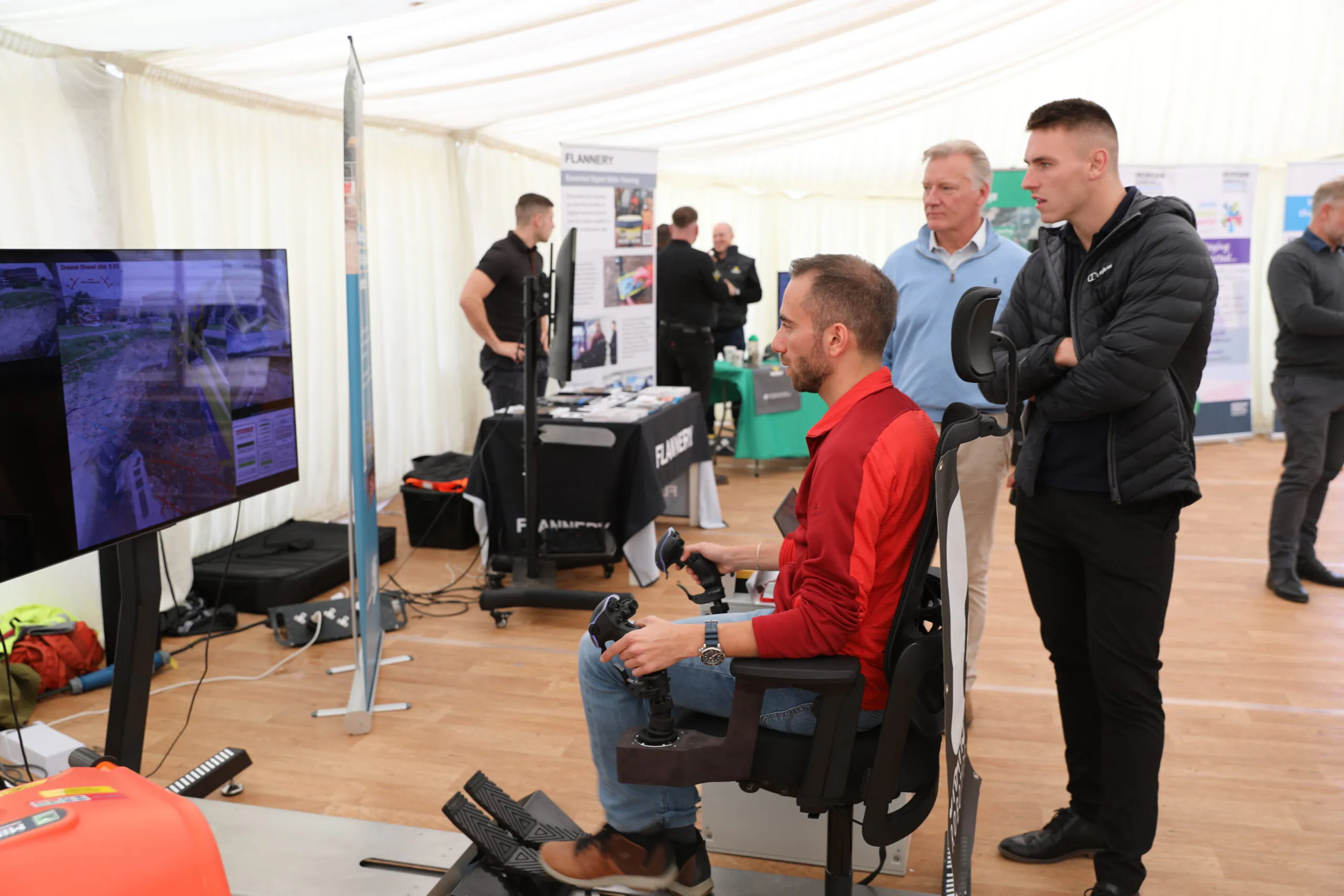 Another view inside the exhibition tent showing attendees interacting around booths displaying infrastructure technology solutions.