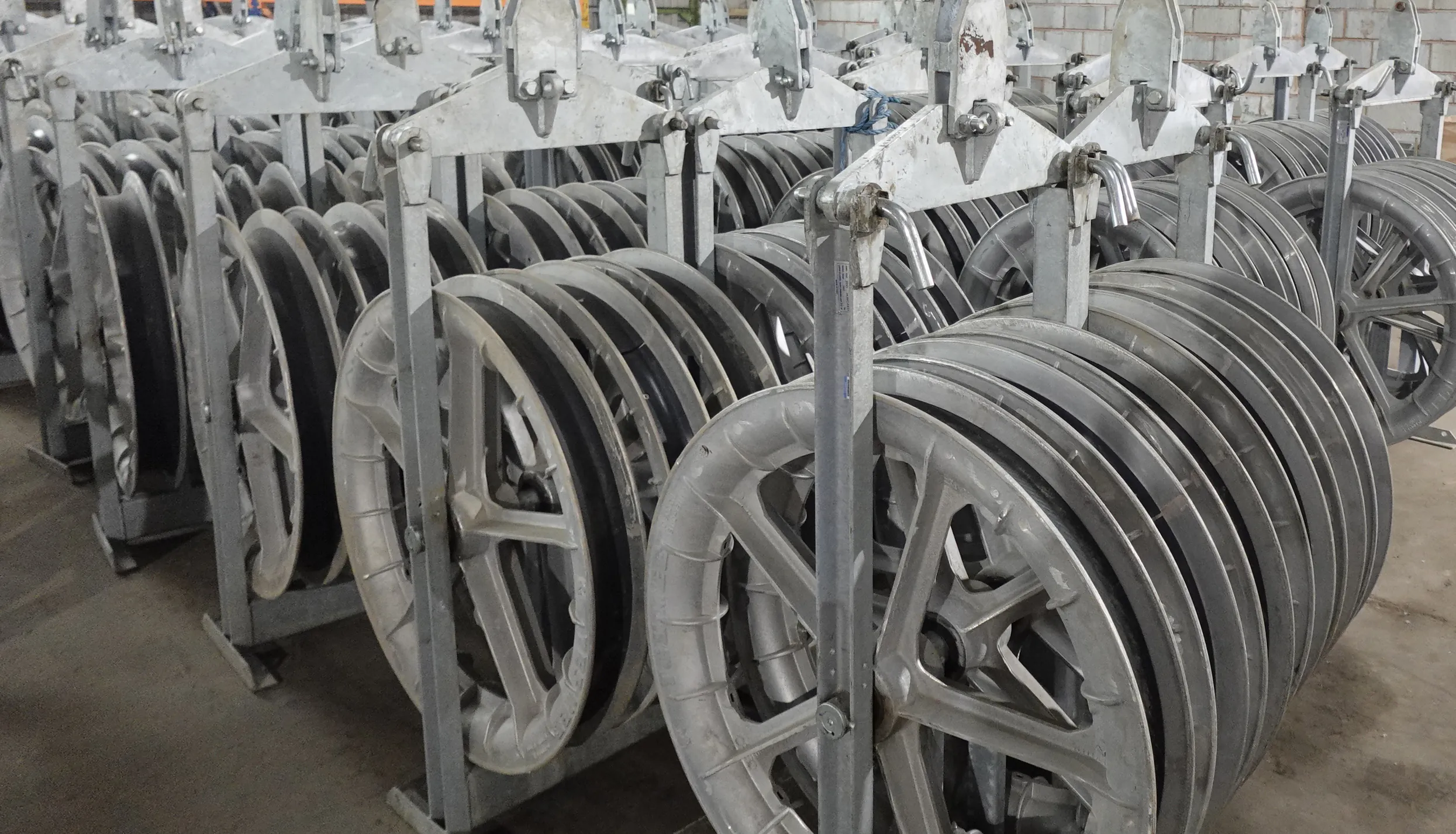 Close-up of cable sheaves used in overhead line installations, mounted on a metal frame with visible wiring.