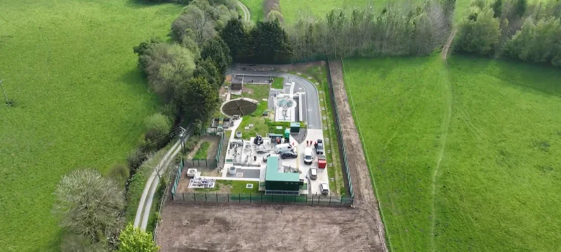 Aerial view of an industrial facility surrounded by green fields and trees.
