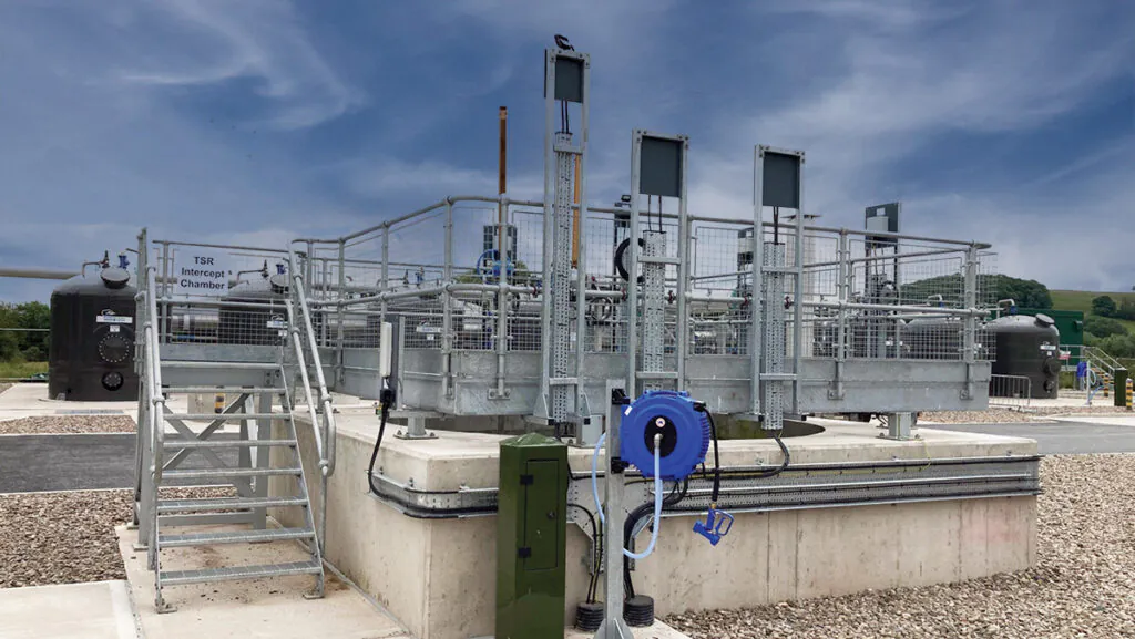 Outdoor industrial setup with metal platforms, railings, and equipment under a partly cloudy sky.