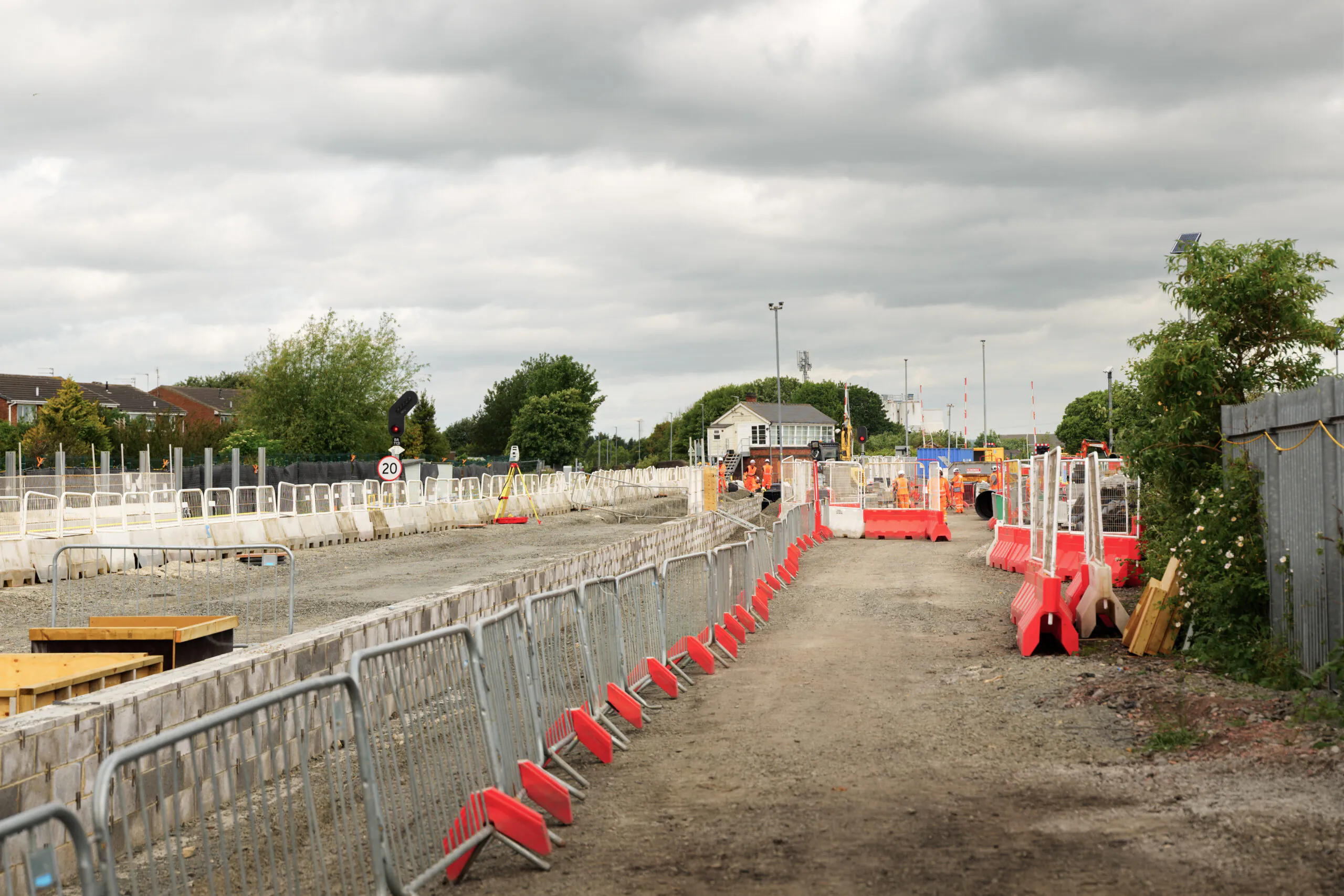 Under-construction railway platform during the day with barriers and scattered construction materials.