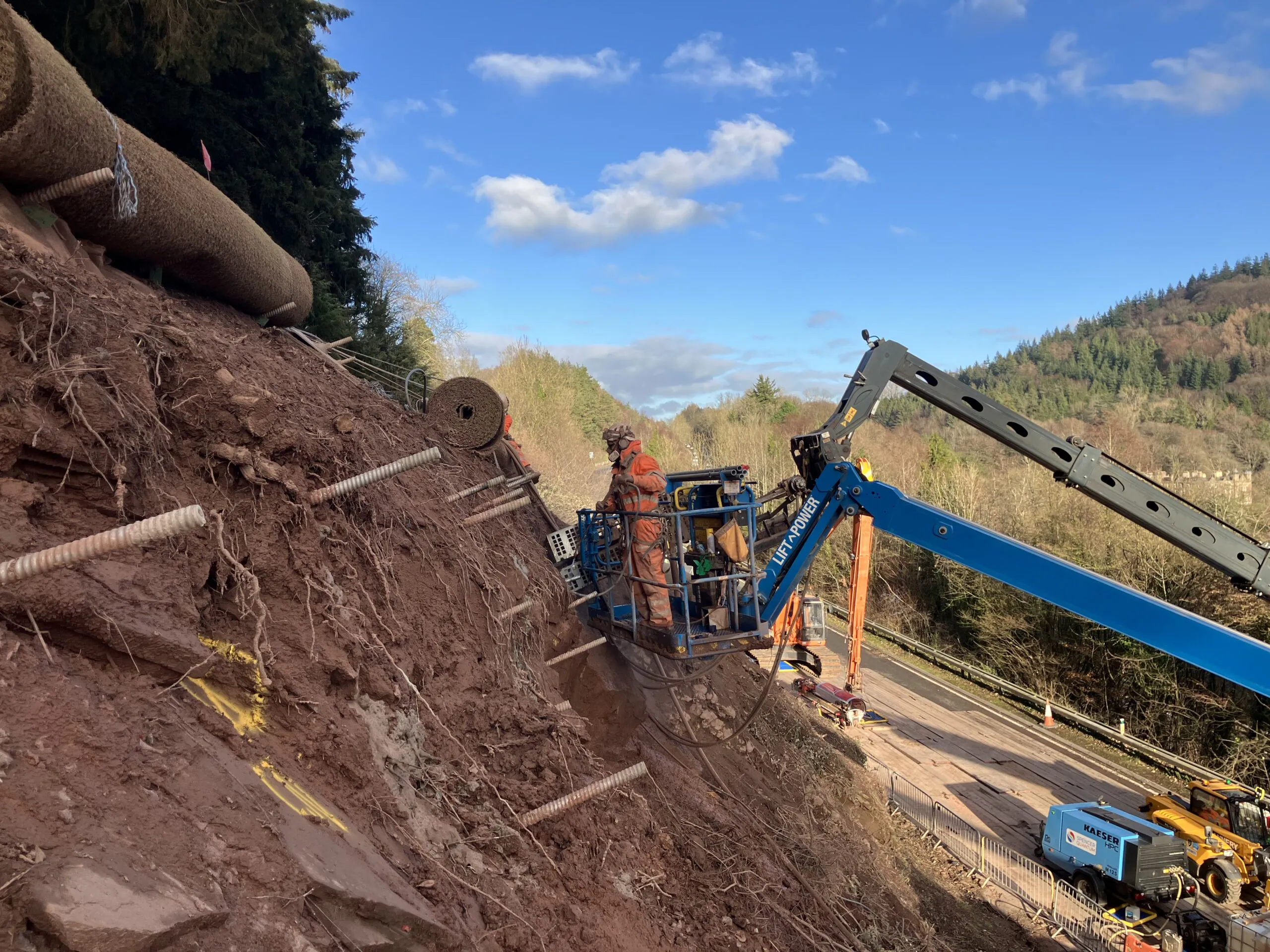 Workers install soil nails into the slope at A40 Leys Bend using a mobile elevated work platform as part of the long-term rockfall stabilisation works.