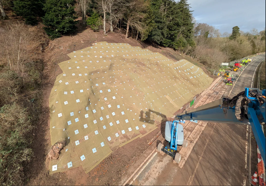Aerial view of the completed slope stabilisation works at A40 Leys Bend, showing erosion control matting and soil nail installations across the hillside.